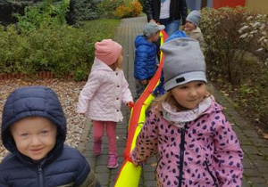 Dzieci idą z wężem na przedszkolny plac zabaw.